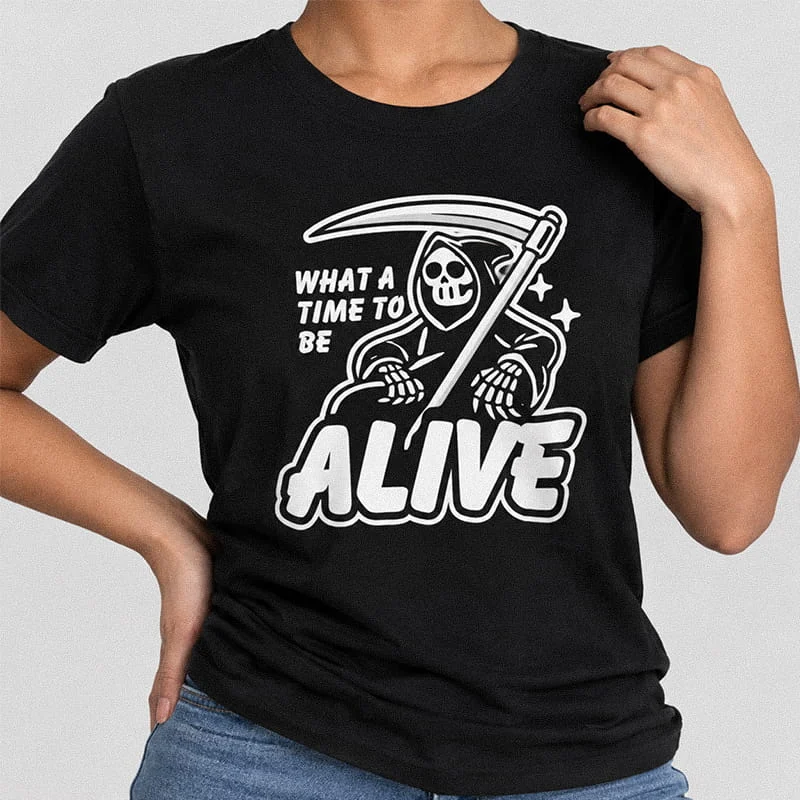 Woman wearing a black What a Time to Be Alive T-Shirt - Funny Grim Reaper with Scythe Tee featuring a hooded Grim Reaper with a scythe surrounded by stars