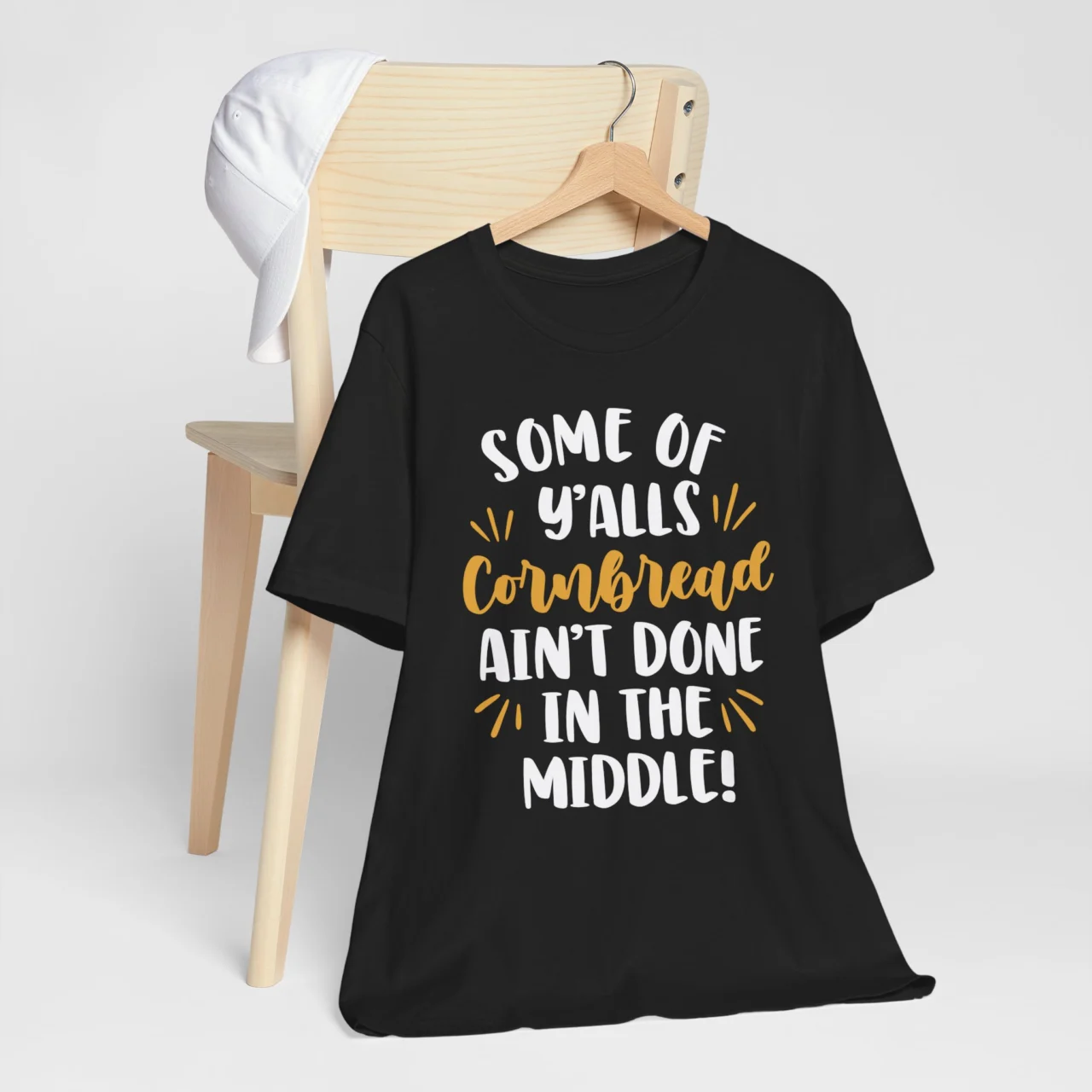 Black Some Of Y'alls Cornbread Ain't Done In The Middle Shirt - Funny Southern Slang Tee on a hanger.