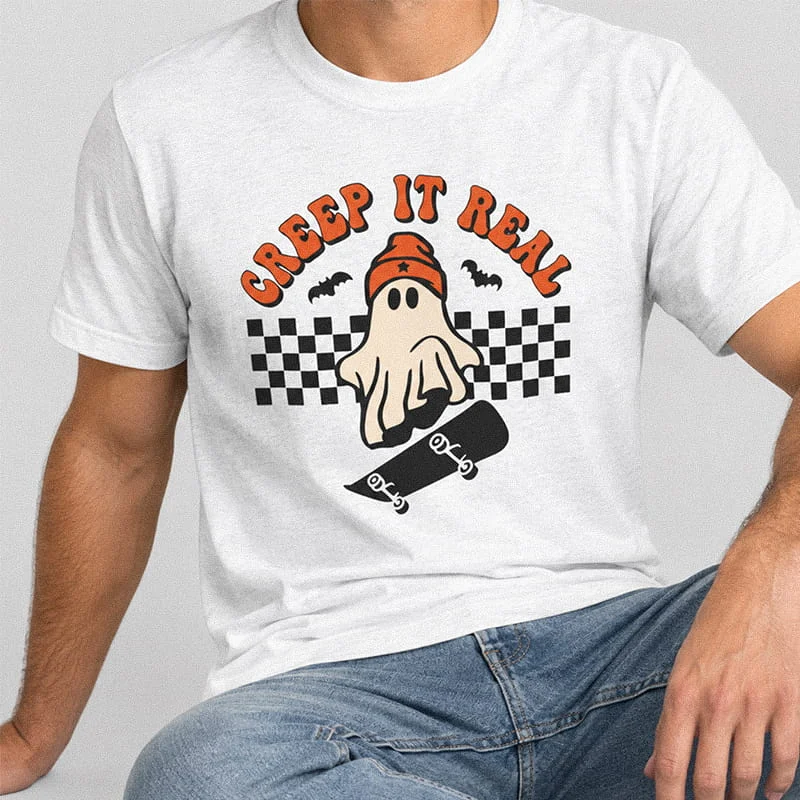 Man wearing an white Creep It Real Shirt - Skater Ghost Tee - Funny Halloween Shirt featuring a ghost in a beanie riding a skateboard with a checkered pattern and text reading Creep It Real