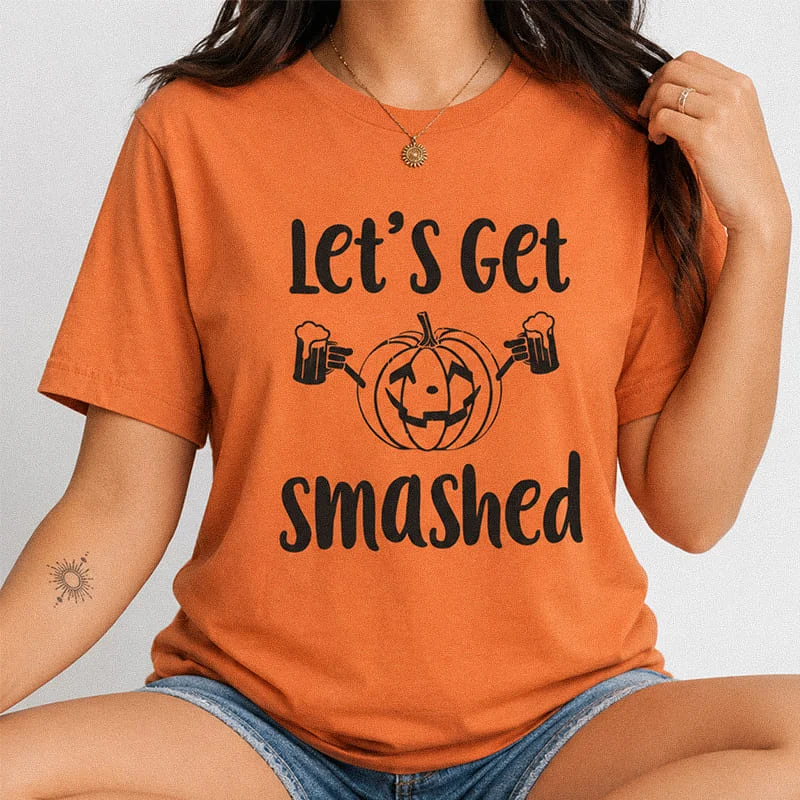 Woman wearing an burnt orange Lets Get Smashed Funny Halloween Drinking Tee featuring a jack-o'-lantern pumpkin holding two beer mugs with the text Let's Get Smashed