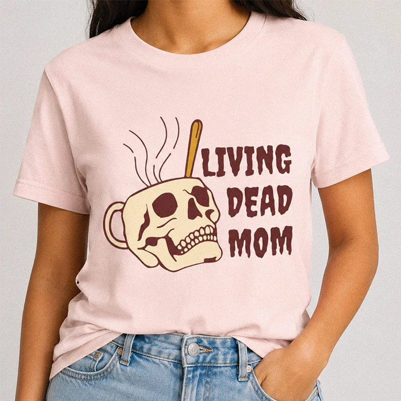 Woman wearing a light pink Living Dead Mom Funny Halloween Mom Tee featuring a skull-shaped steaming coffee mug with the text Living Dead Mom