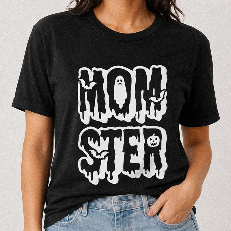 Woman wearing a black Momster Funny Mom Halloween Tee, Spooky Mom Costume Shirt featuring groovy dripping letters with a ghost, bat, and pumpkin reading Momster