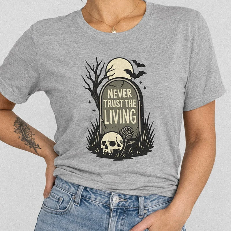 Woman wearing a heather grey Never Trust the Living Shirt - Spooky Halloween Skull Shirt featuring a tombstone inscribed with Never Trust The Living next to a skull, rose, and bats