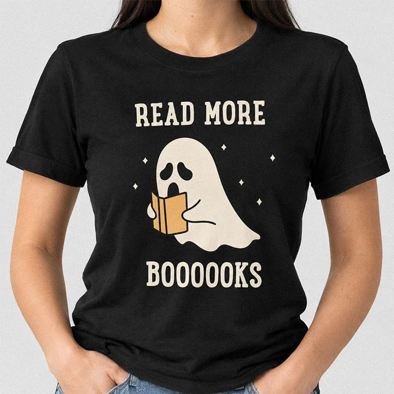 Woman wearing a black Read More Books Ghost T-Shirt - Halloween Book Lover Tee featuring a cute ghost reading an orange book