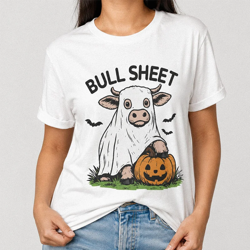 Woman wearing a white funny Bull Sheet Costume Shirt - Funny Ghost Cow Halloween Tee with a cow wearing a ghost sheet standing next to a jack-o'-lantern with the text Bull Sheet