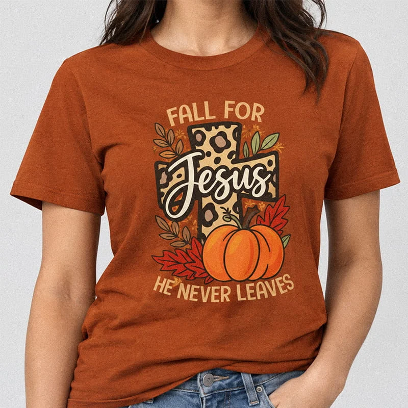 Woman wearing an Autumn color Fall For Jesus He Never Leaves Shirt - Christian Fall Tee with a leopard print cross, pumpkin, and autumn leaves