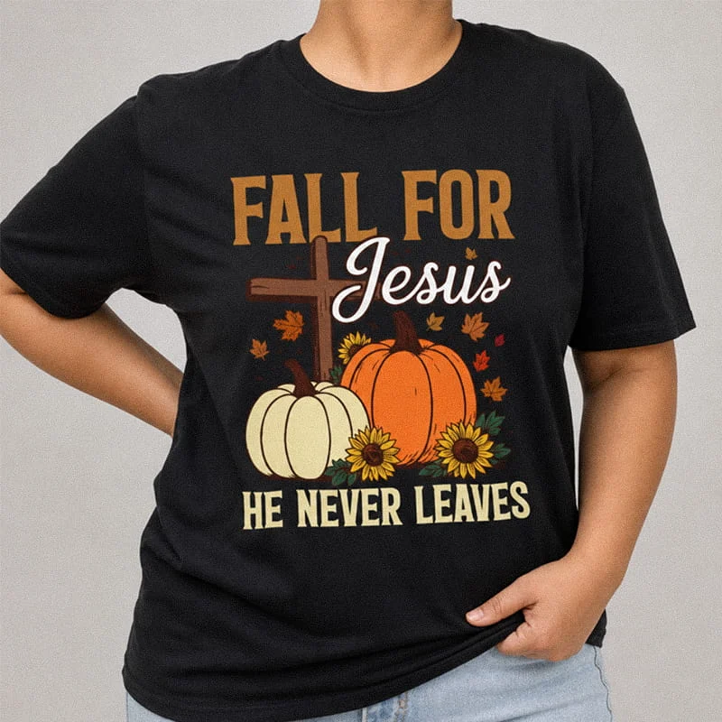 Person wearing a black Fall For Jesus He Never Leaves Christian Shirt - Funny Fall Tee with pumpkins, sunflowers, a wooden cross, and text reading Fall For Jesus He Never Leaves