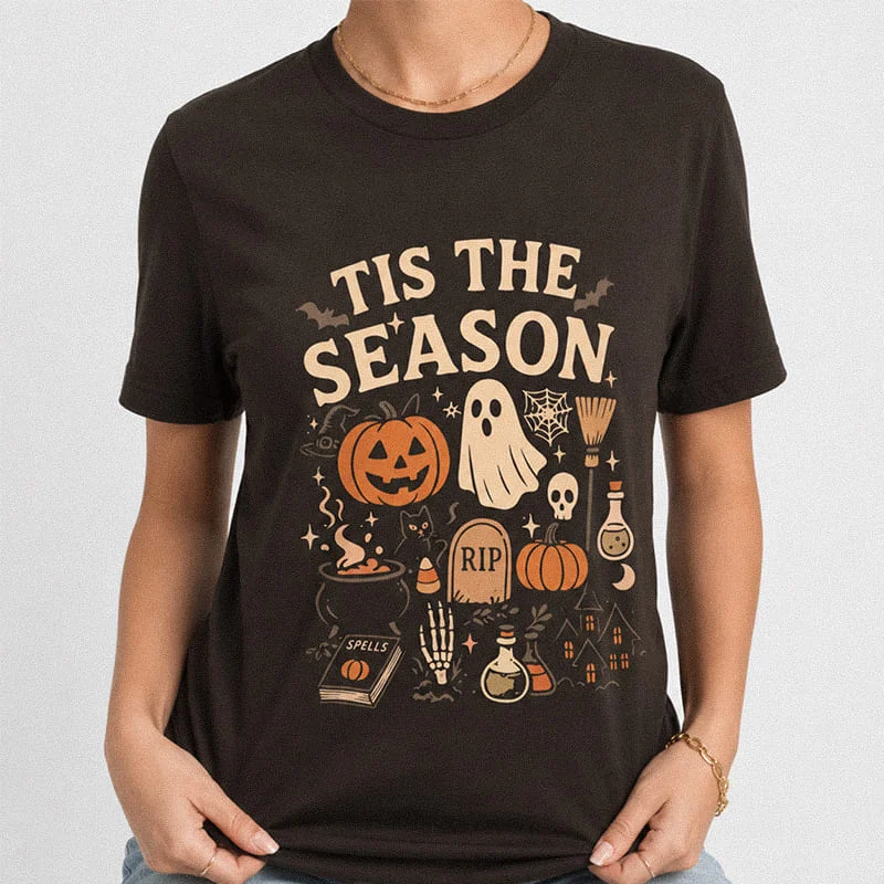 Woman wearing a dark brown Tis The Season Halloween Shirt - Vintage Ghost Pumpkin Tee featuring a ghost, pumpkin, skull, and cauldron reading Tis The Season