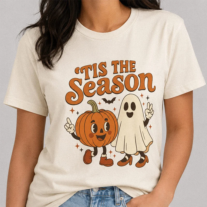 Woman wearing a natural ’Tis The Season Halloween Pumpkin and Ghost Shirt featuring retro cartoon pumpkin and ghost characters flashing peace signs with the text "'Tis The Season"
