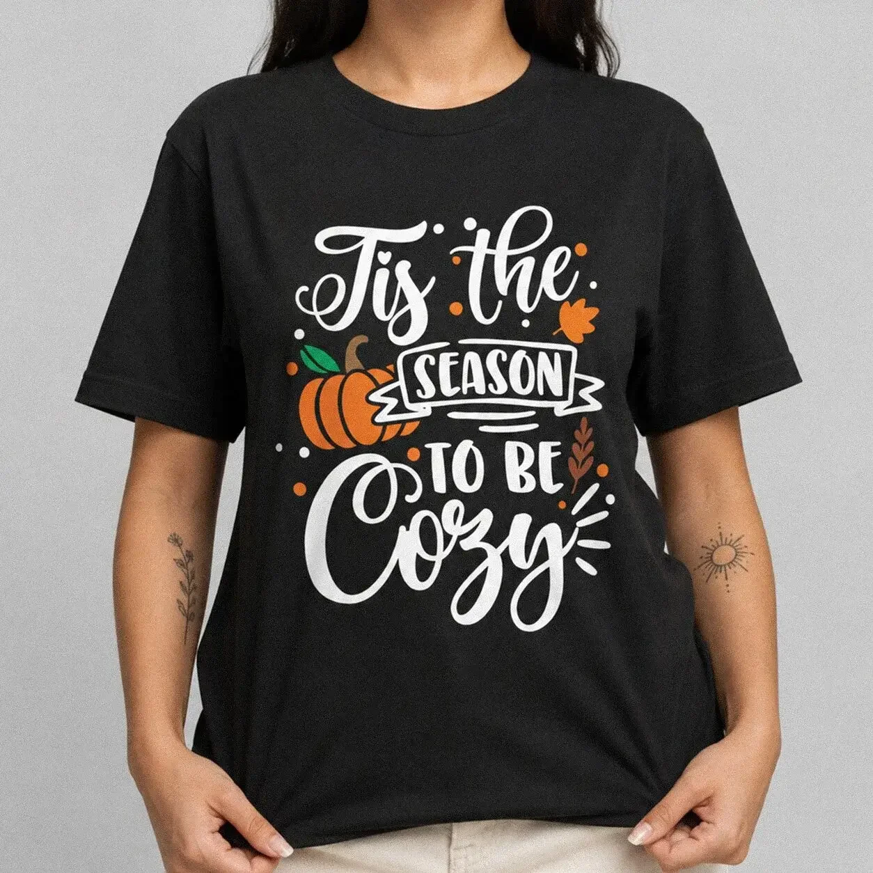 Black Tis The Season To Be Cozy Pumpkin Shirt styled with a pumpkin, leaves, and script text reading "Tis The Season To Be Cozy"