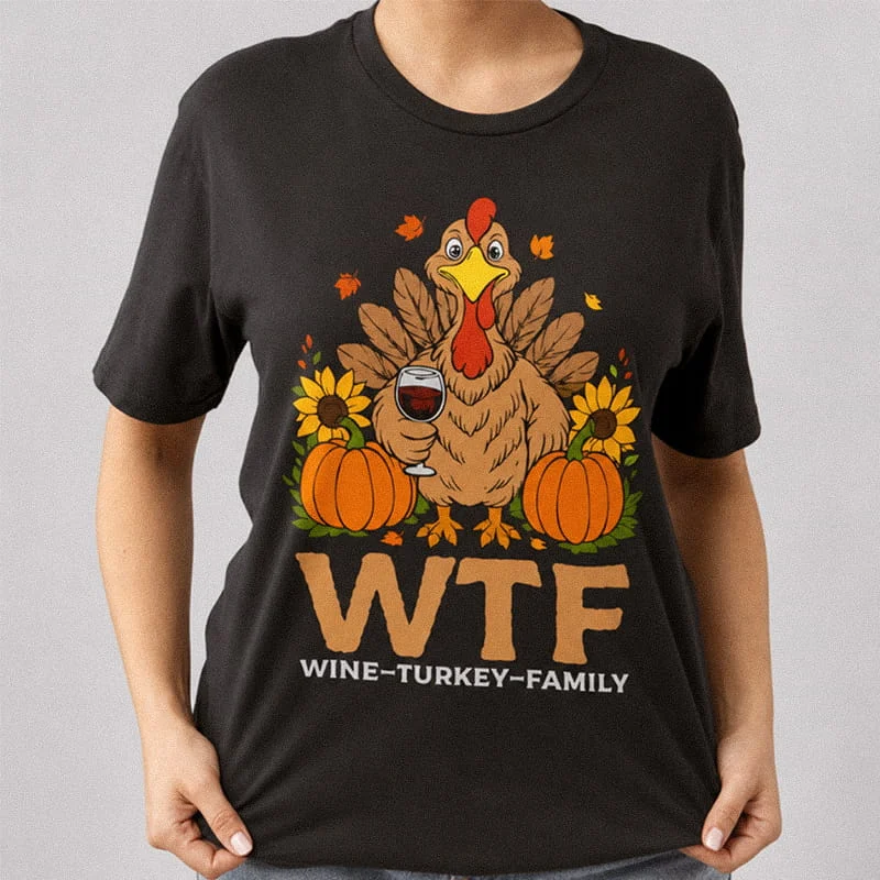 Person wearing a black WTF Wine Turkey Family Shirt - Funny Thanksgiving T-Shirt featuring a turkey holding a glass of red wine between pumpkins and sunflowers with text reading WTF Wine-Turkey-Family